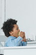 © LIGHTFIELD STUDIOS - side view of adorable african american boy biting apple at home