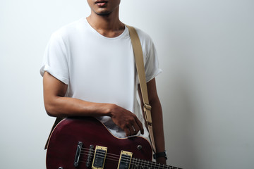 Wall Mural - man in white blank t-shirt with electric guitar, empty wall, studio close-up