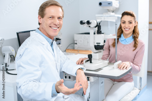 Fotografía smiling ophthalmologist and patient near slit lamp in clinic