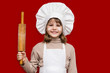 © Svetlana - Happy little girl in chef uniform holds rolling pin isolated on red. Kid chef. Cooking Process Concept