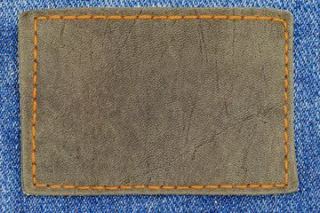 black leather tag with an orange seam on denim blue jeans