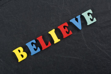 BELIEVE word on black board background composed from colorful abc alphabet block wooden letters, copy space for ad text. Learning english concept.