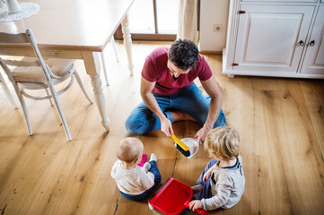 Wall Mural - Father and two toddlers with brush and dustpan.