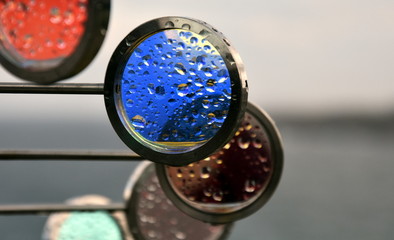 Wet, red and blue, round shaped glass outdoor decoration on a rainy day.