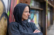 © michaelheim - Woman in a hoodie leaning against graffiti