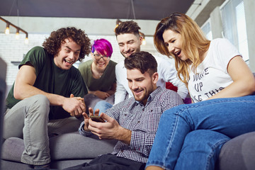 A group of friends at a meeting talking together sitting on a sofa in the room.