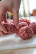 Weibliche Hand nimmt Hackfleisch zur Zubereitung von Fleischbällchen 