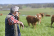© goodluz - Farmer standing in field with cattle in background