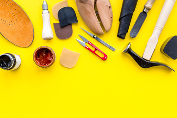 Wall Mural - Instruments and materials for make shoes. Shoemaker's work desk. Hummer, awl, knife, sciccors, wooden shoe, insole, paint and leather. Yellow background top view copy space