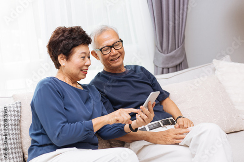 Fotografía Senior Asian couple grandparents using a smart phone together on sofa at home