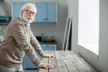 Old Age. Nice Elderly Man Looking At You While Standing In The Kitchen At Home