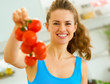 © Alliance - Happy young woman holding bunch of tomato in kitchen
