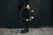 © Sarune Zurba - Low section of man holding cotton boll wreath outdoors