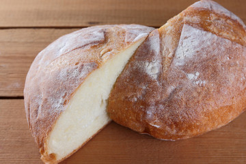 Half-cut bread on a wooden background, two halves of wheat bread from a stove on pine boards, a French dough for a designer, copy space, rustic style, wooden background