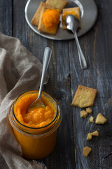 Wall Mural - Healthy raw orange jam with dried apricots in a glass jar with cookies on a wooden table. diet food. selective focus. rustic style