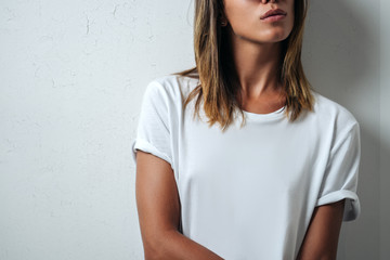 Woman in white blank t-shirt, grunge wall, studio close-up