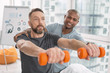 Physical strength. Serious adult man holding dumbbells in front of him while exercising