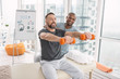 Individual training. Joyful positive man sitting on the medical couch while exercising with dumbbells