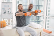 © zinkevych - Pleasant workout. Joyful positive man lifting dumbbells in front of him while enjoying this exercise