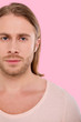 © Viacheslav Yakobchuk - New masculinity. The portrait of a handsome blue-eyed man with a long hair wearing a beige t-shirt and posing for the camera against a pink background