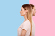 Diverging views. Pleasant young woman and her boyfriend standing in a line but looking into different directions while posing against blue and pink backgrounds respectively