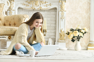 Beautiful teen girl sitting on floor and using laptop