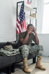 Wall Mural - Upset army soldier sitting on sofa with camouflage clothes