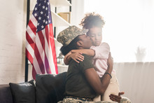 Woman In Camouflage Clothes Kissing Her Daughter