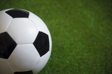 Close up view of a classic black and white football on lush green grass background