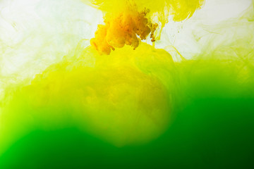 Wall Mural - close up view of mixing of green and yellow paints splashes in water isolated on gray