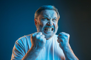 the senior emotional angry man screaming on blue studio background