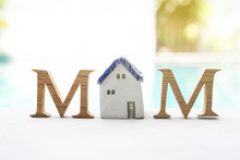Mother's Day Concept, Wooden M Text With Vintage Style Ceramic House Over Blurred Swimming Pool Background, Outdoor Day Light