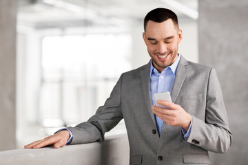 Wall Mural - business people, technology and corporate concept - smiling businessman with smarphone at office