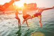 © raisondtre - Group of happy people having fun jumping in the sea water from a pier. Friends in mid air on a sunny day summer pool party. Vacation , friendship , youth concept.