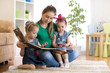 © Oksana Kuzmina - Pretty young mother reading a book to her kids daughters