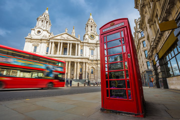 Wall Mural - London, England - Traditional red telephone box with iconic red double-decker bus on the move at St.Paul's Cathedral on a sunny day