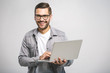 © denis_vermenko - Confident business expert. Confident young handsome man in shirt holding laptop, looking at camera and smiling while standing against white background