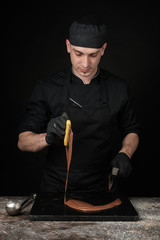 Chocolatier in black uniform in the process of making chocolates