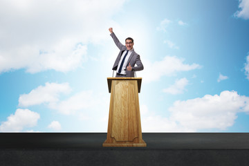 Wall Mural - Man businessman making speech at rostrum in business concept