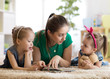 © Oksana Kuzmina - Young mother reading a book to her kids daughters. Children and mom lying on rug in cozy living room.