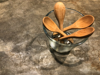 Wooden spoons in glass on the cement floor with cafe light. Vintage style with copy space.