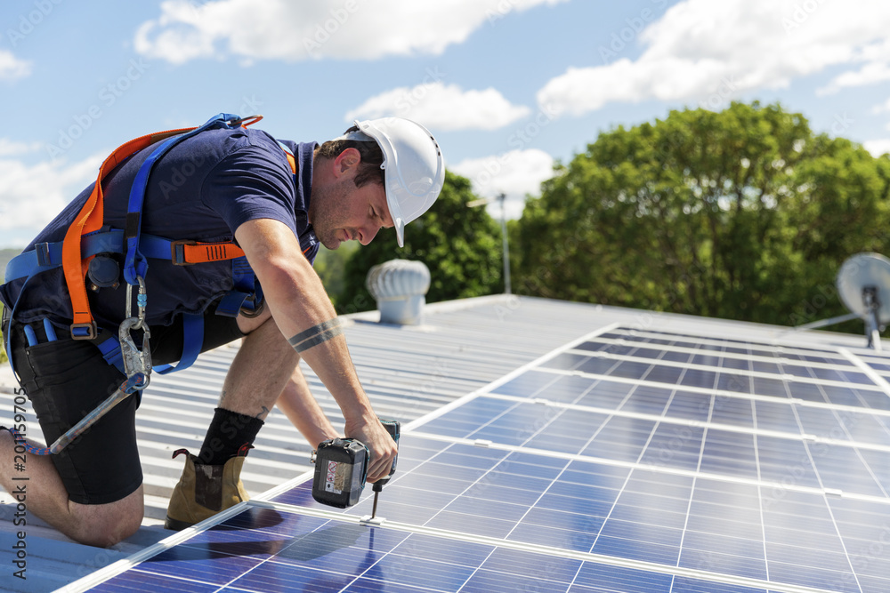 Solar panel technician with drill installing solar panels - obrazy, fototapety, plakaty 