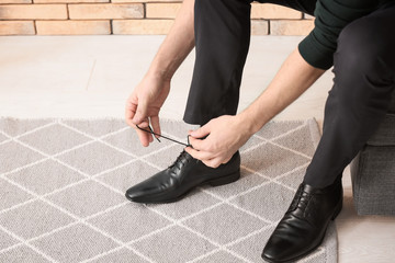 Poster - Man tying shoelaces indoors