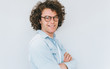 © iuricazac - Horizontal profile view portrait of handsome smiling young male with curly hair, wears denim shirt and round trendy spectacles, looking to the camera. Copy space for advertisement. People race concept