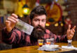 Hipster holds money, cash to buy more alcohol.