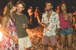 © DisobeyArt - Happy friends drinking beer at beach festival with bonfire in background