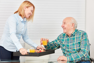 Wall Mural - Junge Frau serviert Senior das Frühstück