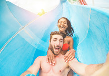 Young Happy Friends Having Fun In Aqua Park Pipe  During Weekend Holidays - Crazy Multi Race Couple Taking Selfie Photo With Funny Faces - Summer Vacation, Travel And Love Concept