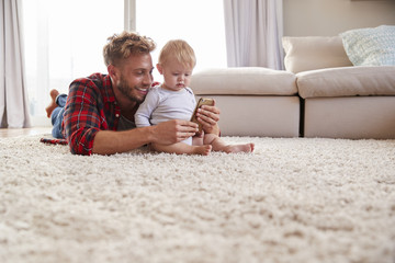 Wall Mural - Young father taking selfie with toddler son in sitting room