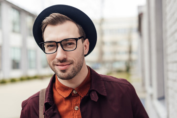 handsome smiling young man in trendy hat and eyeglasses